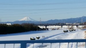 雪の河川敷の先に真っ白い富士山